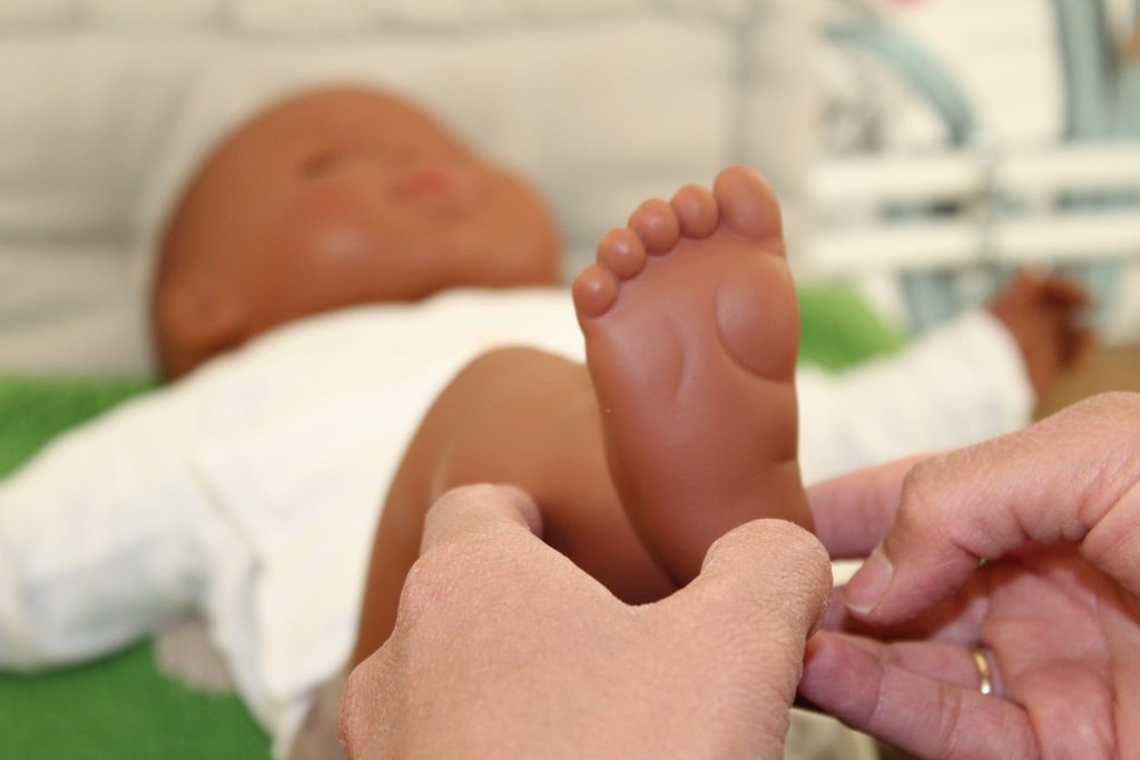 Atelier de réflexologie bébé émotionnelle sur les pieds d'une poupée