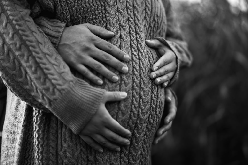 femme enceinte avec les mains de son conjoint et les siennes sur son ventre